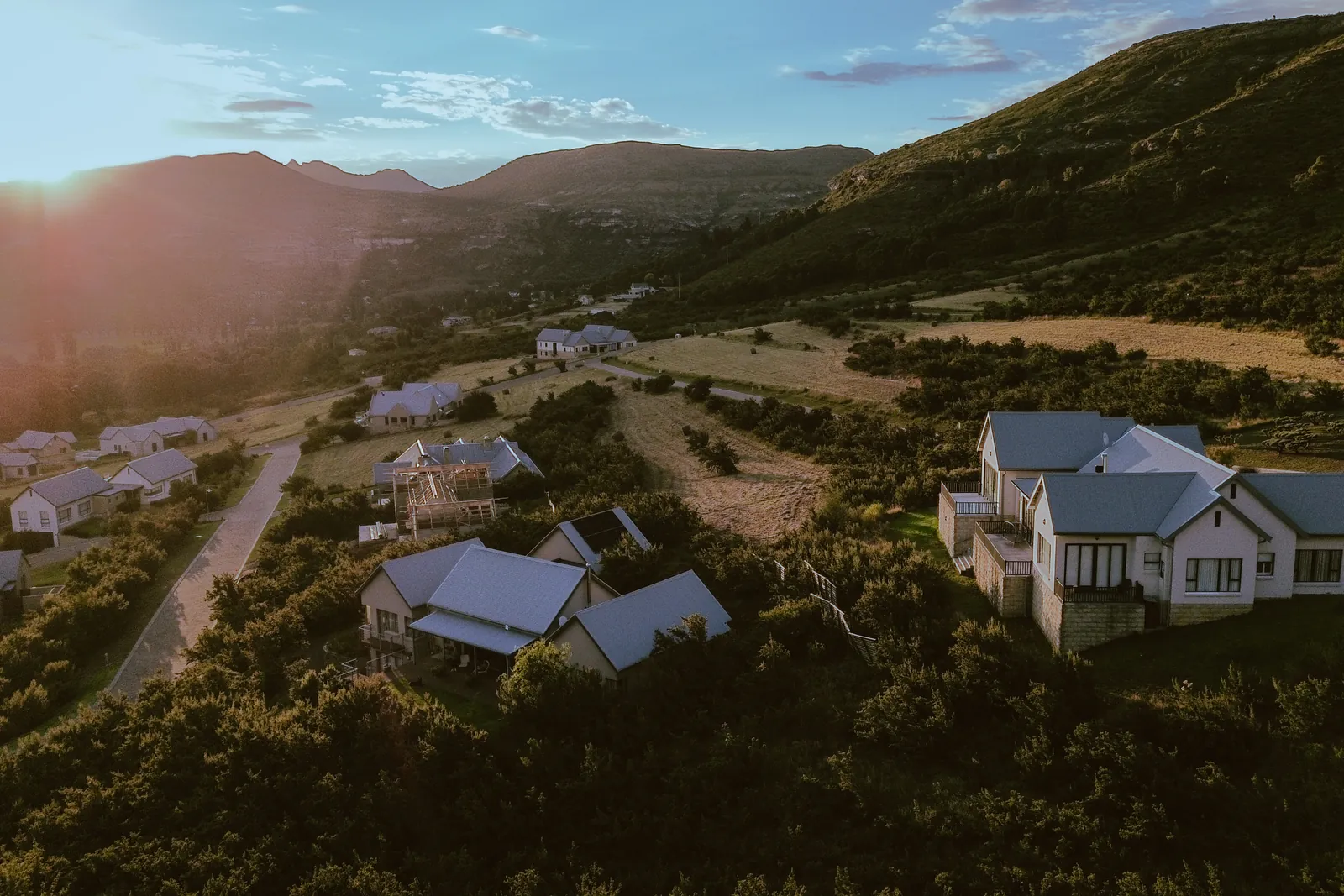 Aerial view over homes at Clarens Mountain Estate in low evening sun, with the ridge behind