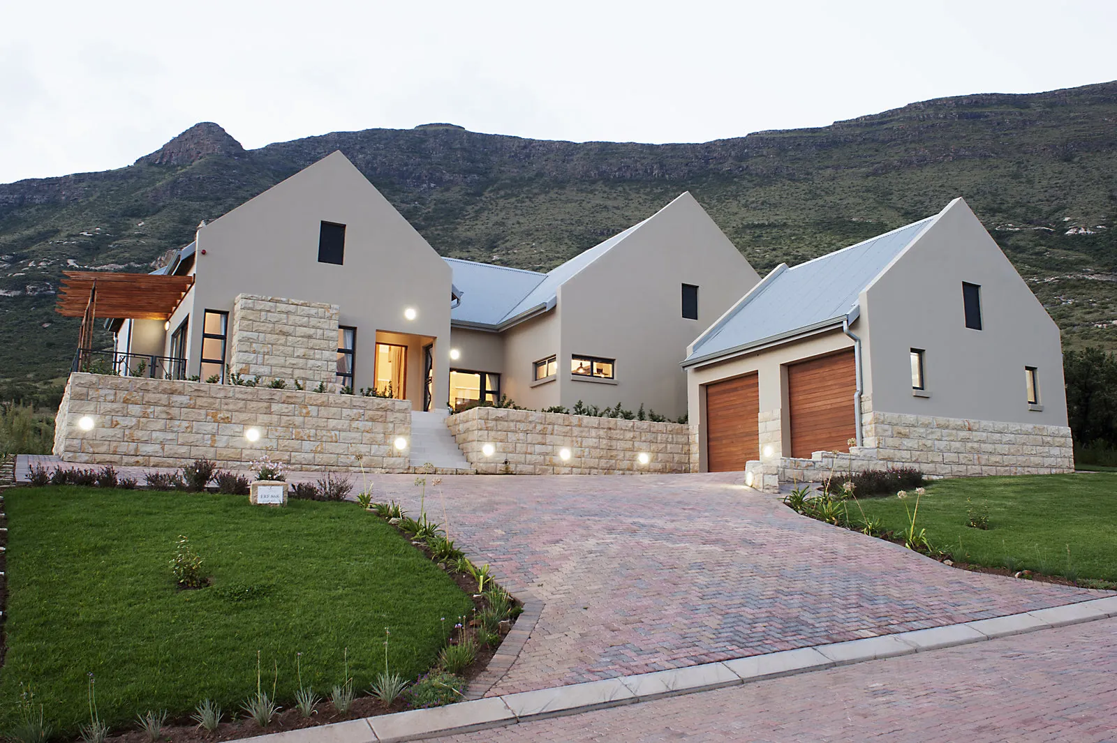 A sandstone and glass home on the estate, lit at dusk