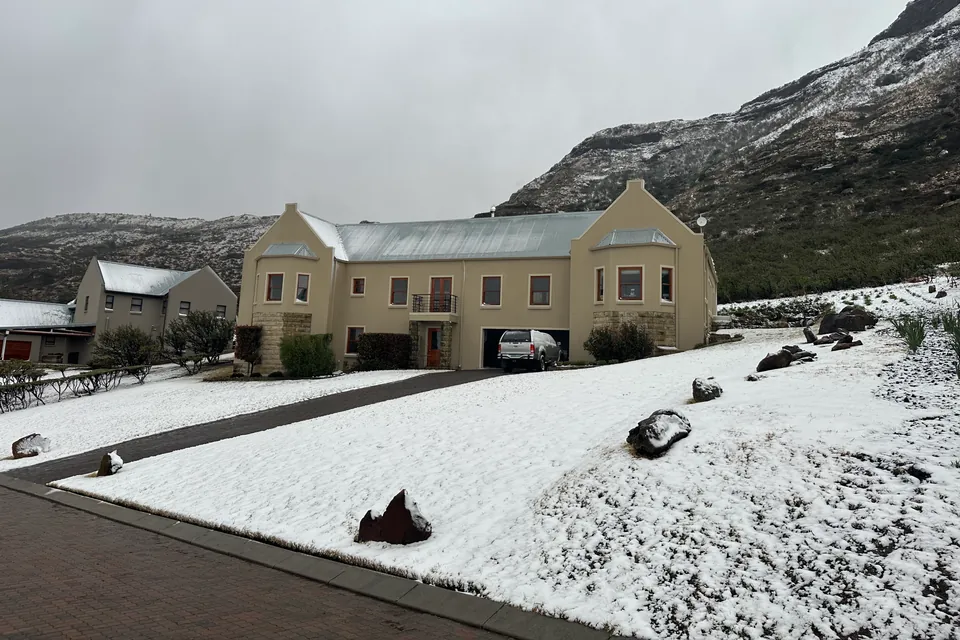 An estate home under snow, with the mountain white behind it