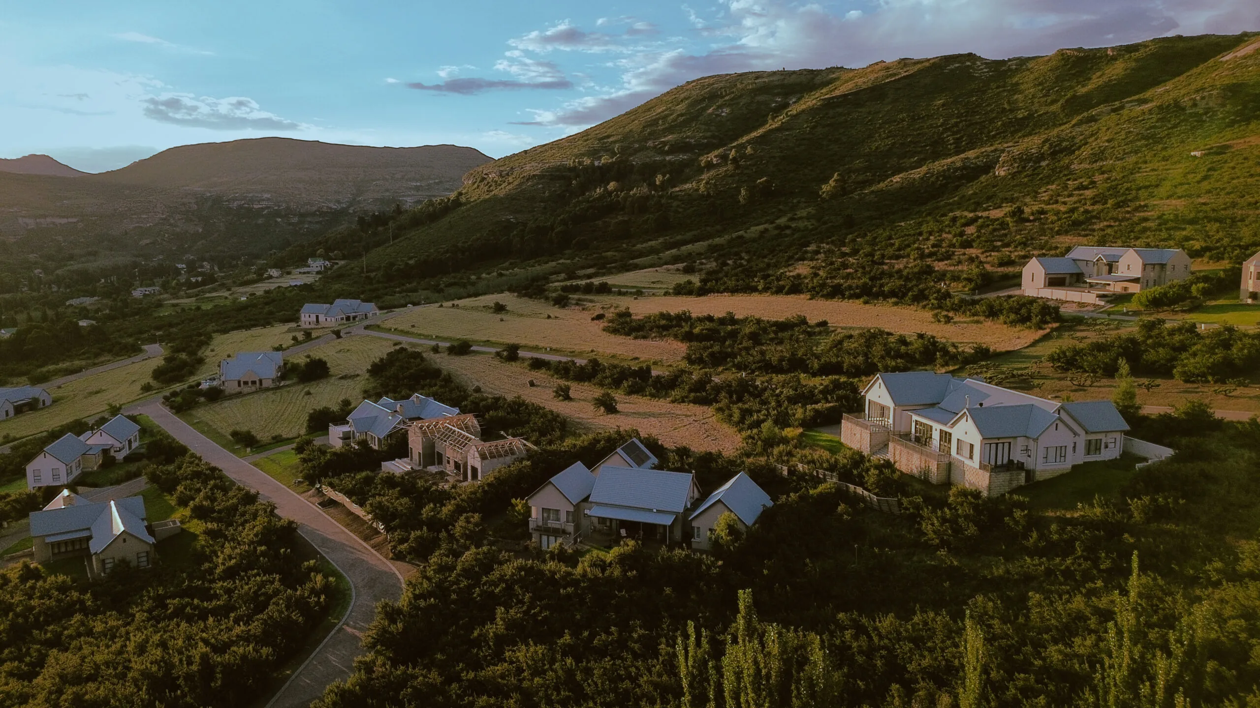 Estate homes set among green belts, with the mountain ridge rising behind