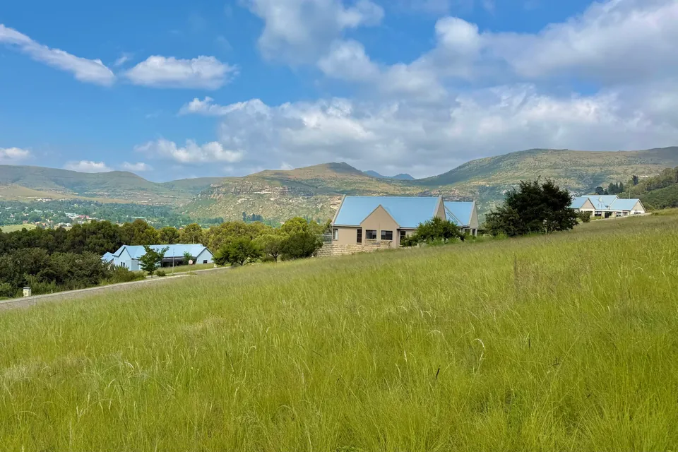 Open grassland on the estate with a home and the mountain ridge beyond